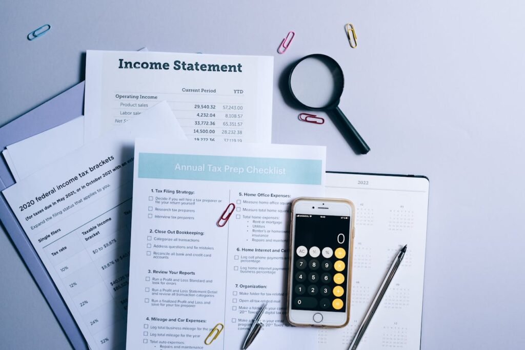 A Mobile Phone and Documents Near the Magnifying Glass on the Table